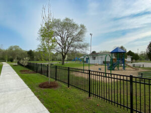 Park with fenced playground and trees.