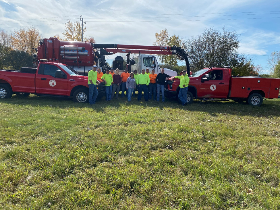 public services staff by vehicle Group of workers with red trucks on grass