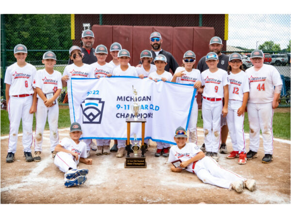 Youth baseball team holding championship banner and trophy.