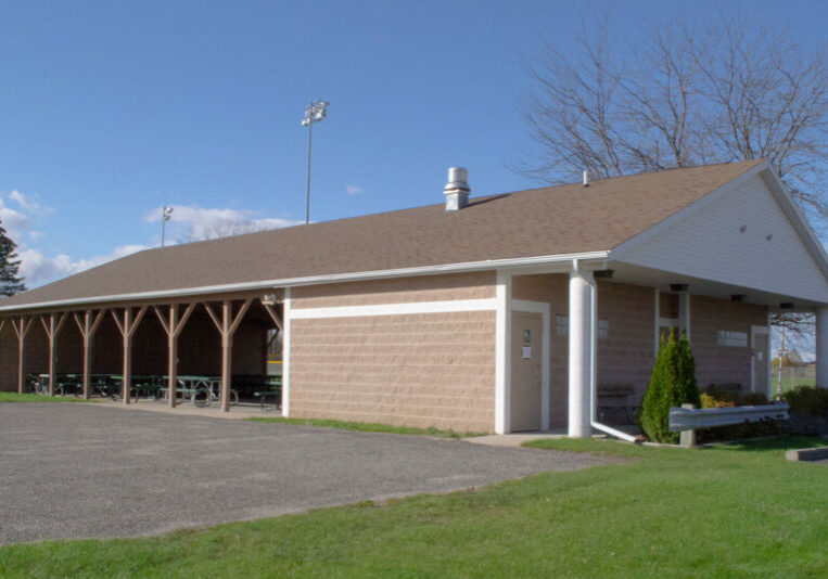 Community park pavilion with picnic tables and field.