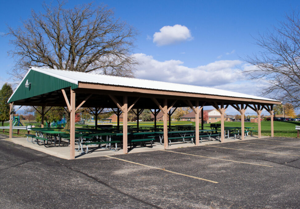 Park pavilion with picnic tables, clear blue sky.